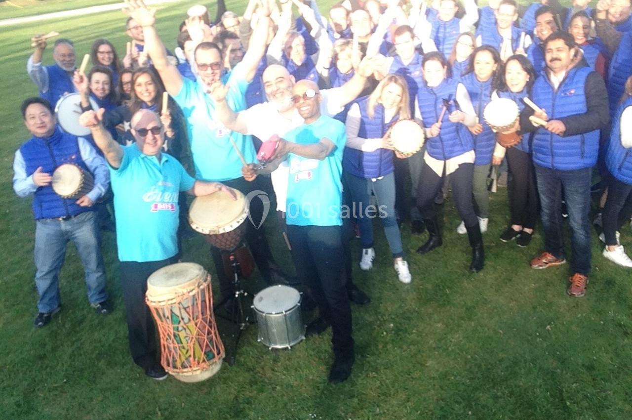 Un groupe de personnes en plein air joue des percussions et pose joyeusement pour une photo.