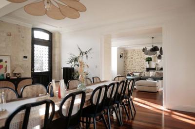 Baignoire blanche près d'une fenêtre, avec deux flacons de savon sur un tabouret en bois dans un espace lumineux.
