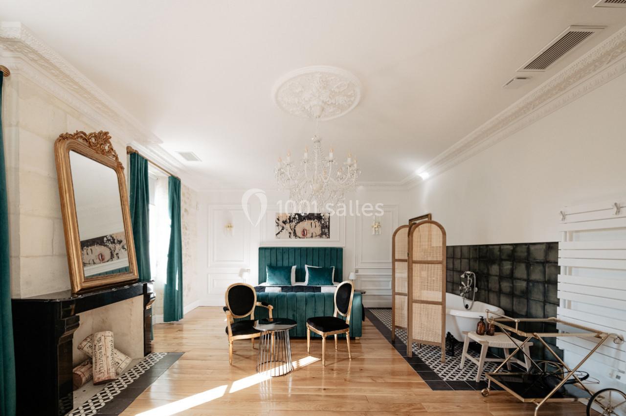 Chambre élégante avec lit double, baignoire sur pieds, miroir doré, mobilier vert et détails décoratifs raffinés.