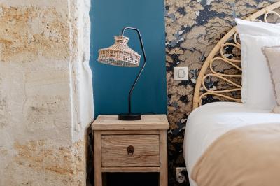 Baignoire blanche près d'une fenêtre, avec deux flacons de savon sur un tabouret en bois dans un espace lumineux.