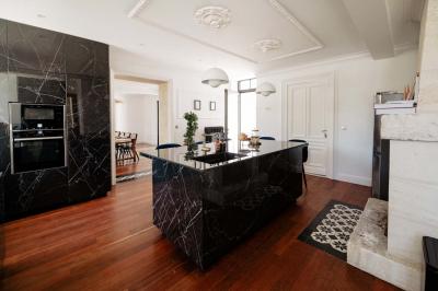Baignoire blanche près d'une fenêtre, avec deux flacons de savon sur un tabouret en bois dans un espace lumineux.