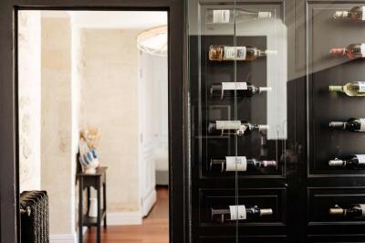Baignoire blanche près d'une fenêtre, avec deux flacons de savon sur un tabouret en bois dans un espace lumineux.