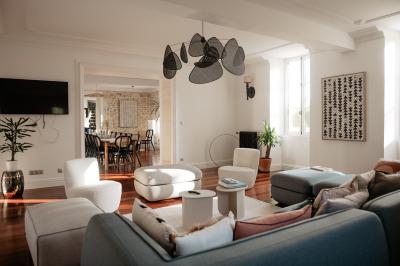 Baignoire blanche près d'une fenêtre, avec deux flacons de savon sur un tabouret en bois dans un espace lumineux.