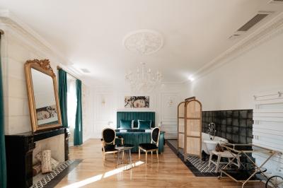 Vue d'une salle de bain avec une baignoire blanche, un tabouret en bois portant deux flacons, et une vitre donnant sur un…