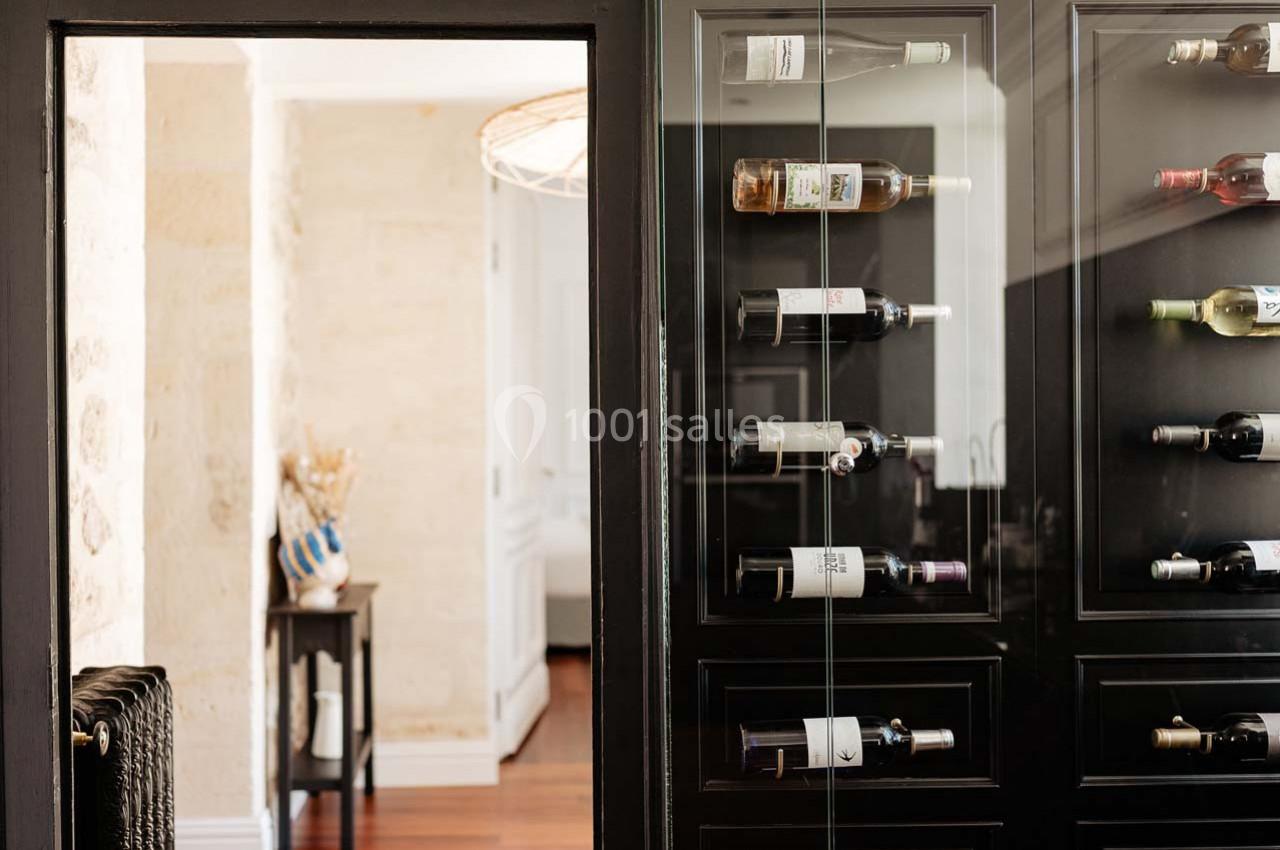 Cave à vin moderne avec des bouteilles disposées horizontalement dans un meuble vitré, intérieur lumineux en arrière-plan.