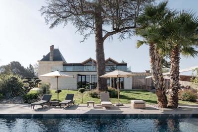 Vue d'une salle de bain avec une baignoire blanche, un tabouret en bois portant deux flacons, et une vitre donnant sur un…
