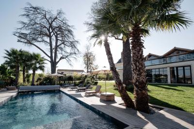 Vue d'une salle de bain avec une baignoire blanche, un tabouret en bois portant deux flacons, et une vitre donnant sur un…