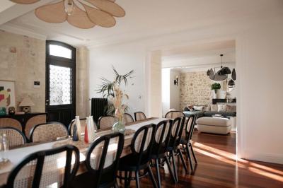 Vue d'une salle de bain avec une baignoire blanche, un tabouret en bois portant deux flacons, et une vitre donnant sur un…