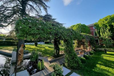 Statue en pierre représentant une femme tenant des épis de blé, placée au centre d'un bassin dans un jardin verdoyant.