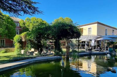 Statue en pierre représentant une femme tenant des épis de blé, placée au centre d'un bassin dans un jardin verdoyant.