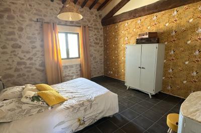 Chambre lumineuse avec deux lits simples, un bureau, une armoire en bois et une fenêtre donnant sur un jardin.