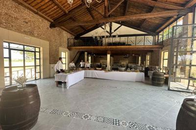 Paysage rural avec un chemin en gravier, des plantes, des champs verdoyants et un ciel partiellement nuageux.