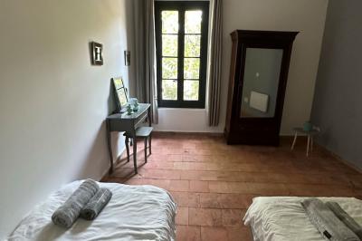 Paysage rural avec un chemin en gravier, des plantes, des champs verdoyants et un ciel partiellement nuageux.