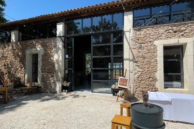 Paysage rural avec un chemin en gravier, des plantes, des champs verdoyants et un ciel partiellement nuageux.