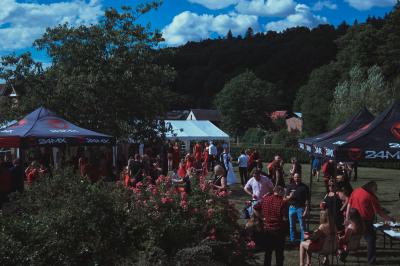 Salle décorée pour un événement avec des tables dressées en noir, rouge et blanc, et des chaises assorties.