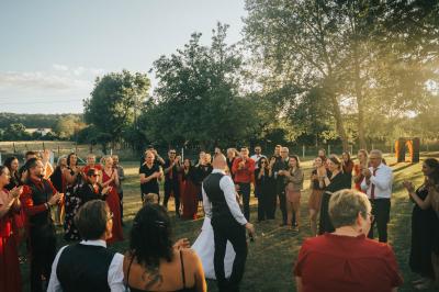 Salle décorée pour un événement avec des tables dressées en noir, rouge et blanc, et des chaises assorties.