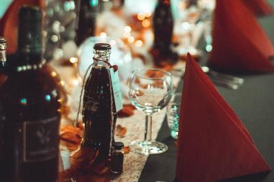 Salle décorée pour un événement avec des tables dressées en noir, rouge et blanc, et des chaises assorties.