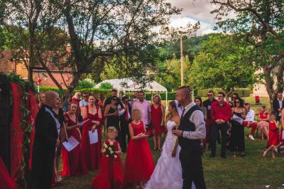 Salle décorée pour un événement avec des tables dressées en noir, rouge et blanc, et des chaises assorties.