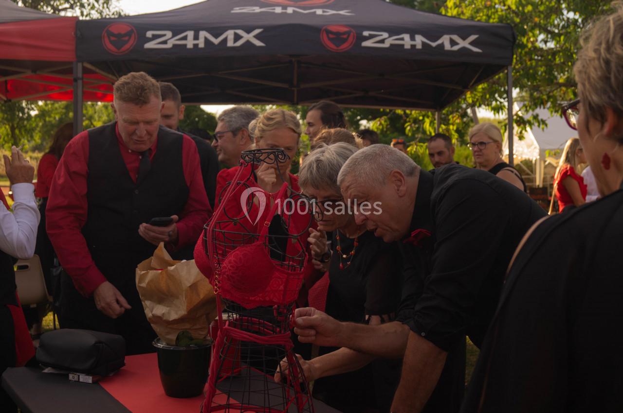 Des personnes observent un mannequin métallique décoré d'un soutien-gorge rouge lors d'un événement en plein air.