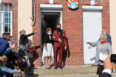 Salle décorée pour un événement avec des tables dressées en noir, rouge et blanc, et des chaises assorties.