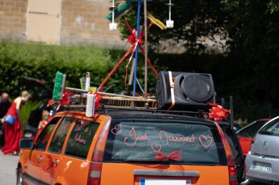 Salle décorée pour un événement avec des tables dressées en noir, rouge et blanc, et des chaises assorties.