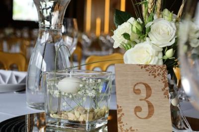 Centre de table avec une carafe d'eau, un vase contenant une bougie flottante, des fleurs blanches et un numéro 3 en bois.