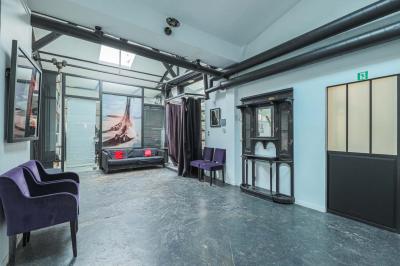 Balcon étroit avec sol en bois, mur en pierre, grillage métallique et vue sur un jardin arboré.