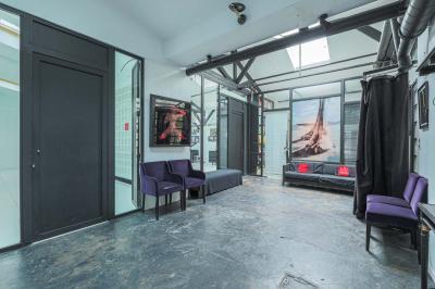 Balcon étroit avec sol en bois, mur en pierre, grillage métallique et vue sur un jardin arboré.