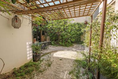 Balcon étroit avec sol en bois, mur en pierre, grillage métallique et vue sur un jardin arboré.