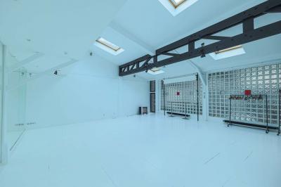 Balcon étroit avec sol en bois, mur en pierre, grillage métallique et vue sur un jardin arboré.