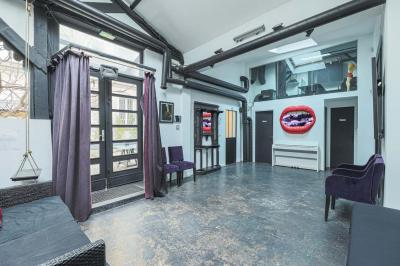 Balcon étroit avec sol en bois, mur en pierre, grillage métallique et vue sur un jardin arboré.