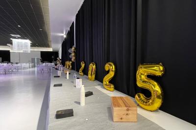 Salle de réception décorée avec des chaises blanches alignées et des arrangements floraux, prête pour un événement.
