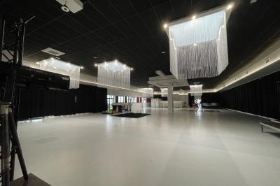 Salle de réception décorée avec des chaises blanches alignées et des arrangements floraux, prête pour un événement.