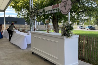 Miniature Location salle Artigues-près-Bordeaux (Gironde) - Espace Descartes Réceptions #33 Bar mobile blanc décoré de fleurs et de verres suspendus, installé en extérieur sous une tente près d'un espace arboré.