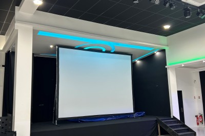 Salle de réception avec des rangées de chaises blanches, tapis rouge au premier plan et drapeaux français et marocain sur…