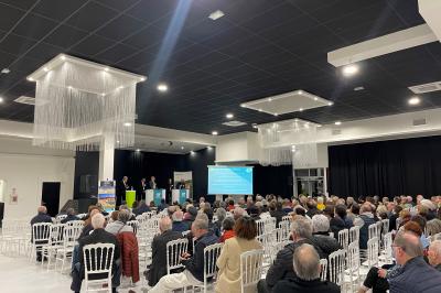 Deux roll-ups promotionnels et une table noire avec des boîtes en bois dans une salle lumineuse au sol blanc.