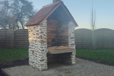 Un grand arbre illuminé par des guirlandes lumineuses dans un jardin avec des tables et chaises en soirée.