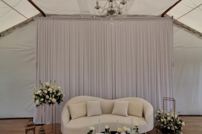 Un grand arbre illuminé par des guirlandes lumineuses dans un jardin avec des tables et chaises en soirée.