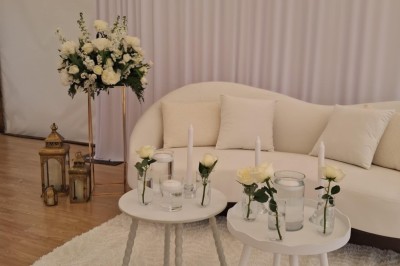 Un grand arbre illuminé par des guirlandes lumineuses dans un jardin avec des tables et chaises en soirée.