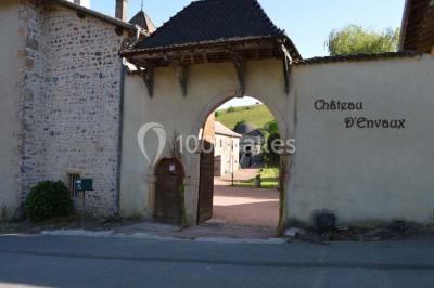 Deux bouteilles de vin, une blanche et une rouge, posées sur un tonneau en bois avec un fond de verdure.