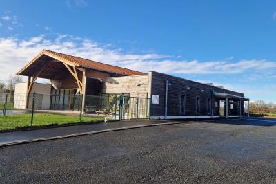 Salle de réception décorée avec des tables rondes, des chaises transparentes et des compositions florales roses et blanches.