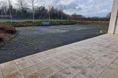 Salle de réception décorée avec des tables rondes, des chaises transparentes et des compositions florales roses et blanches.