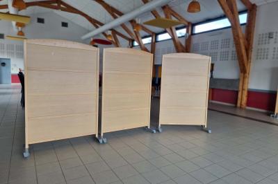 Salle de réception décorée avec des tables rondes, des chaises transparentes et des compositions florales roses et blanches.