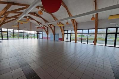 Salle de réception décorée avec des tables rondes, des chaises transparentes et des compositions florales roses et blanches.