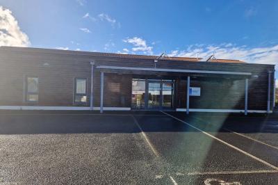 Salle de réception décorée avec des tables rondes, des chaises transparentes et des compositions florales roses et blanches.