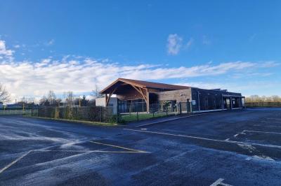 Salle de réception décorée avec des tables rondes, des chaises transparentes et des compositions florales roses et blanches.