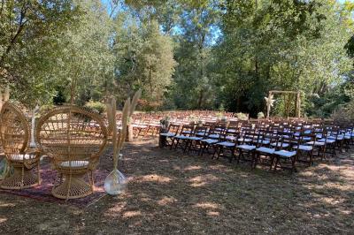 Terrasse aménagée pour un événement avec tables hautes drapées de noir, guirlandes lumineuses et végétation en arrière-plan.