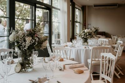 Terrasse aménagée pour un événement avec tables hautes drapées de noir, guirlandes lumineuses et végétation en arrière-plan.