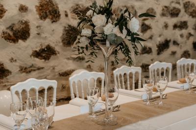 Terrasse aménagée pour un événement avec tables hautes drapées de noir, guirlandes lumineuses et végétation en arrière-plan.