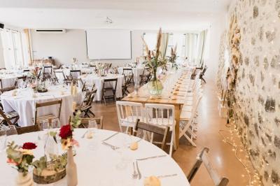 Terrasse aménagée pour un événement avec tables hautes drapées de noir, guirlandes lumineuses et végétation en arrière-plan.